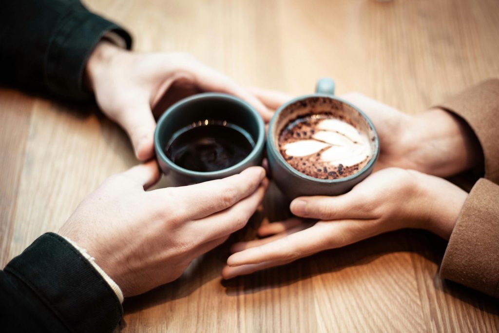 Two people holding hands over coffee cups on an early date